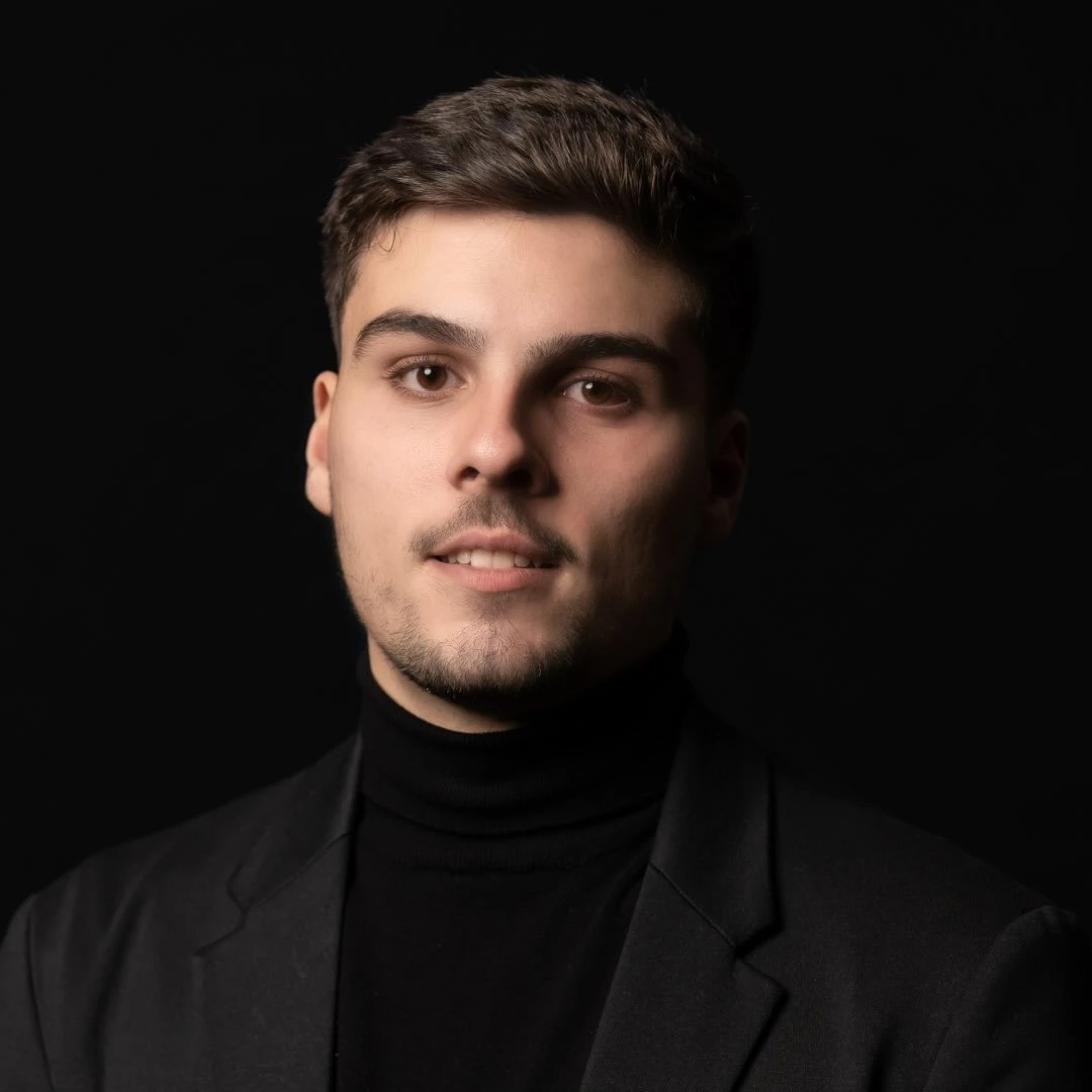 Portrait du fondateur d’Aime Deux Studio, col roulé noir et veste sombre sur fond noir